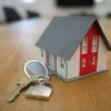 miniature house on a desk with normal sized house keys beside it